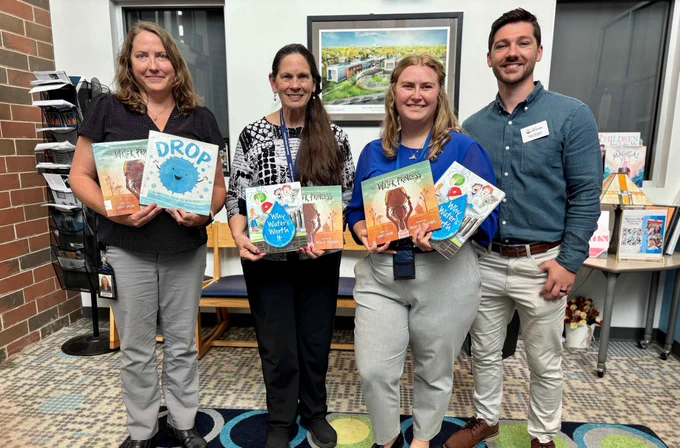 3 employees and a volunteer coordinator holding children's books 