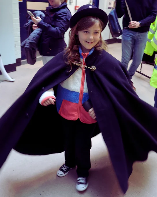 A young girl tries on a police cape and helmet