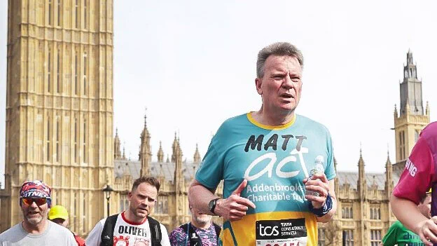 Runners in a marathon with Big Ben in the background. A man in a teal shirt is prominent.