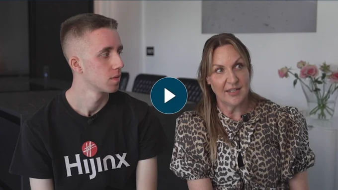 A young man with short, dark hair wearing a black 'Hijinx' t-shirt and an older lady with blonde hair wearing a leopard print t-shirt.