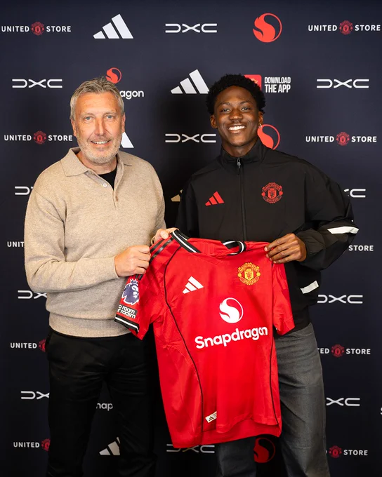 Jason Wilcox takes a photo with Kobbie Mainoo holding up a United home shirt, after Kobbie commits to the club!