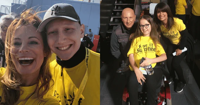 Volunteers in yellow Rays of Sunshine shirts smiling with a girl in a wheelchair at a charity event.