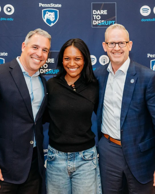 From left to right: Dare to Disrupt podcast host Ryan Newman, guest Asia Grant, and Penn State Smeal College of Business Dean Corey Phelps. All three posing in front of a Penn State and Dare to Disrupt branded backdrop. 