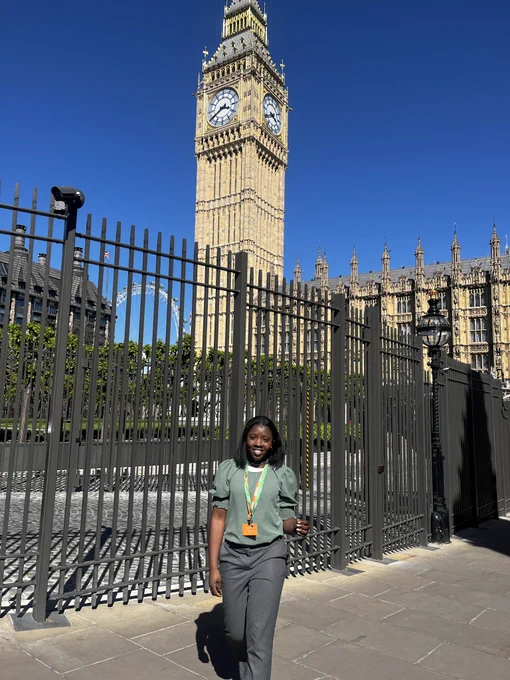 Myself wearing grey trousers and a green top posing in front of Big Ben