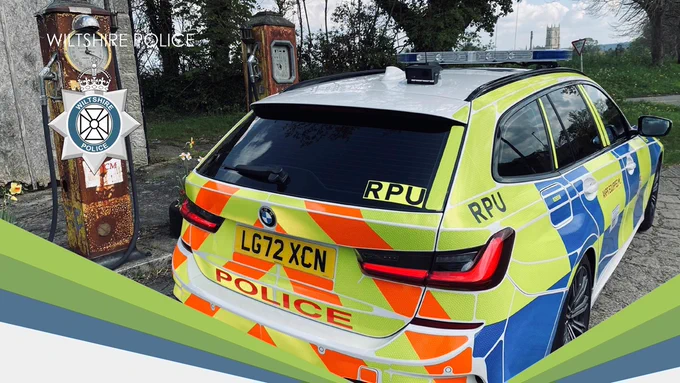 Wiltshire Police BMW estate car with Battenberg livery parked next to a vintage petrol pump.