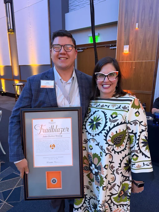 Jake Buller-Young, winner of the Trailblazer Award, and Marieke Van Puymbroeck, Dean of the Graduate School, standing together displaying the Trailblazer certificate.