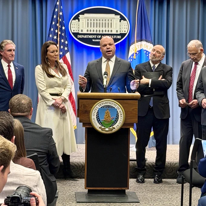 Mr. Telle stands at a podium among a group of individuals