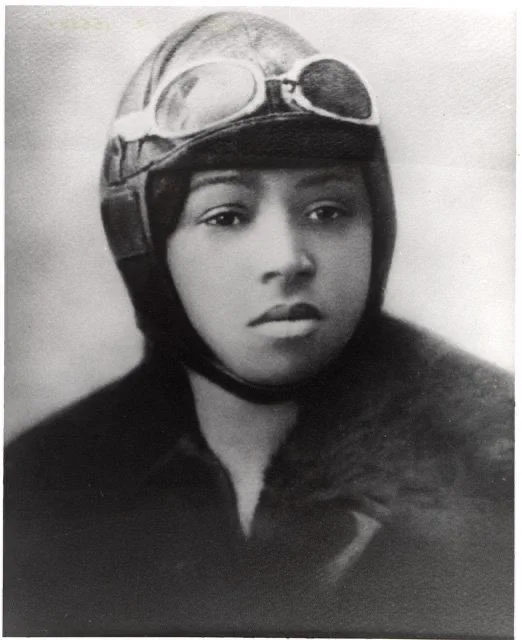 Black and white portrait of Bessie Coleman wearing an early pilot’s headgear.