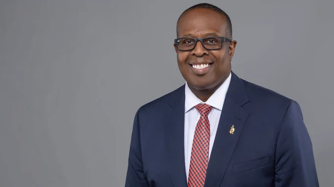 Portrait photo of Dean Samuel Graham smiling at camera and wearing a blue suit with a red tie.
