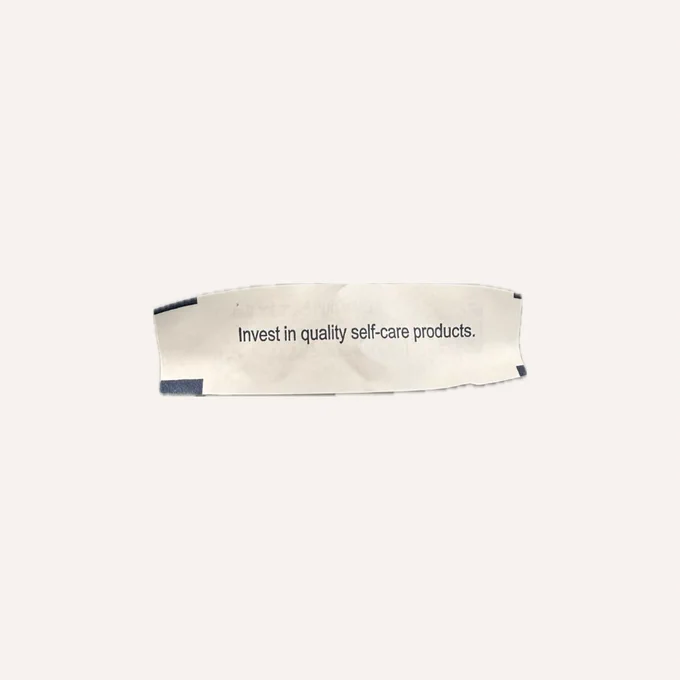 A picture of a fortune cookie paper that says, “Invest in quality self-care products.”