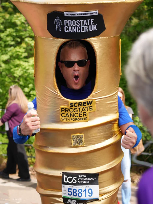 A person in a golden screw costume promoting Prostate Cancer UK. The costume displays the message "Screw Prostate Cancer".