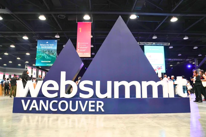 Photograph of a large Web Summit Vancouver sign displayed at a conference venue with a purple mountain-shaped backdrop.