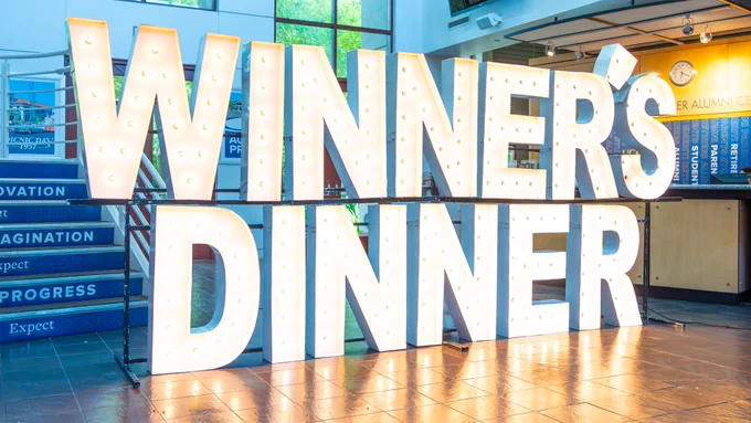 Sign that is lit and has lights that says Winner’s Dinner