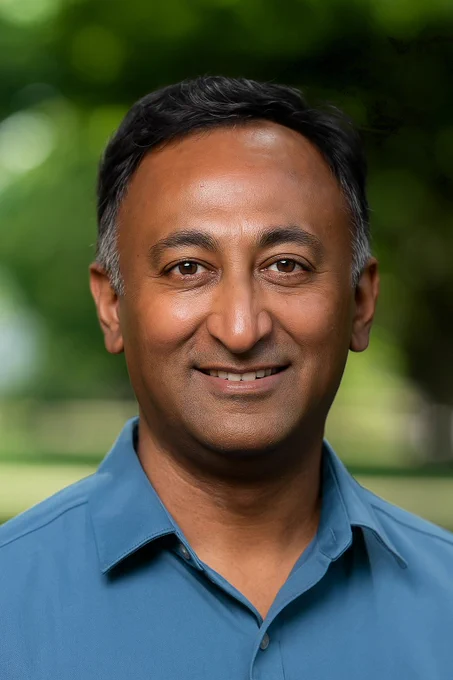 Headshot of a man with black hair in a blue shirt