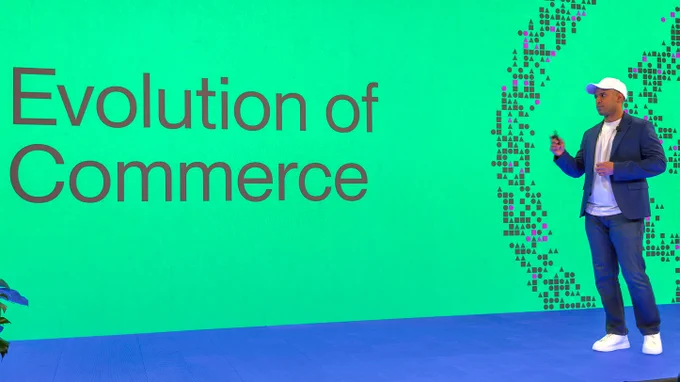 Nikil, CEO of Alchemy, on stage explaining the evolution of commerce at CoBuild