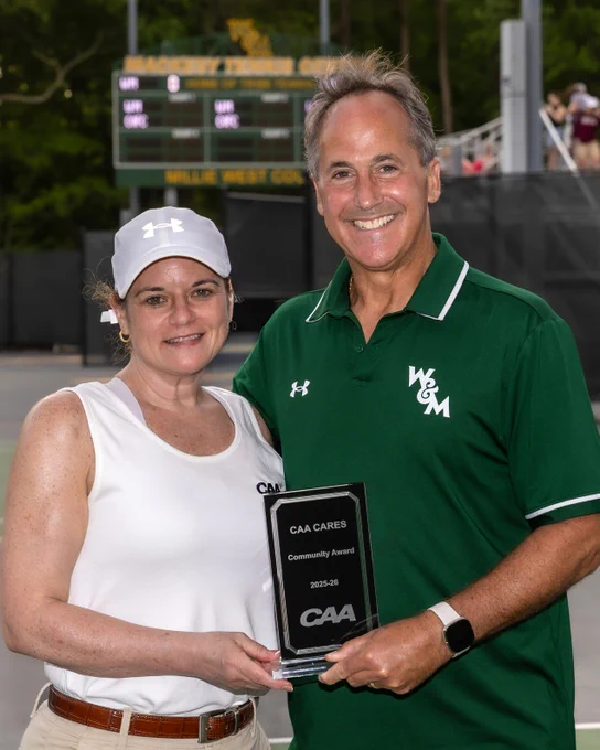 Marc Elim (left) is presented with a glass trophy by CAA Deputy Commissioner Jennifer Condaras, celebrating him as the winner of the CAA Cares Award at the 2026 CAA Tennis Championships played at the Mackesy Tennis Center on the campus of William & Mary. 