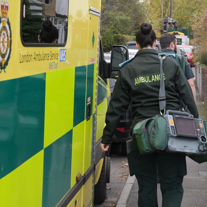 Two ambulance clinicians carrying life-saving equipment on their way to see a patient. 