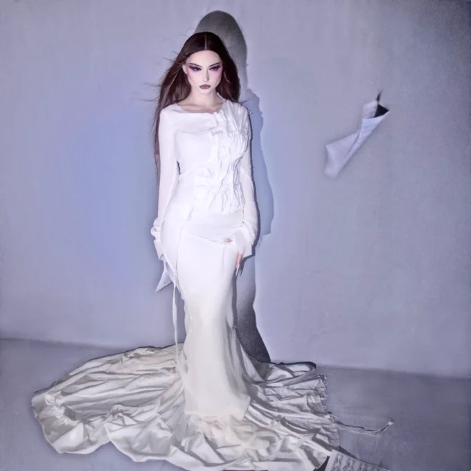 artwork for the single. this is a picture of me, standing in front of a greyish white background, with white lighting. i’m wearing a dramatic textured off-white siren long-sleeve dress. there’s a piece of sheet music in the air next to me. i have long brown hair, dramatic makeup and blush, and white press-on nails.