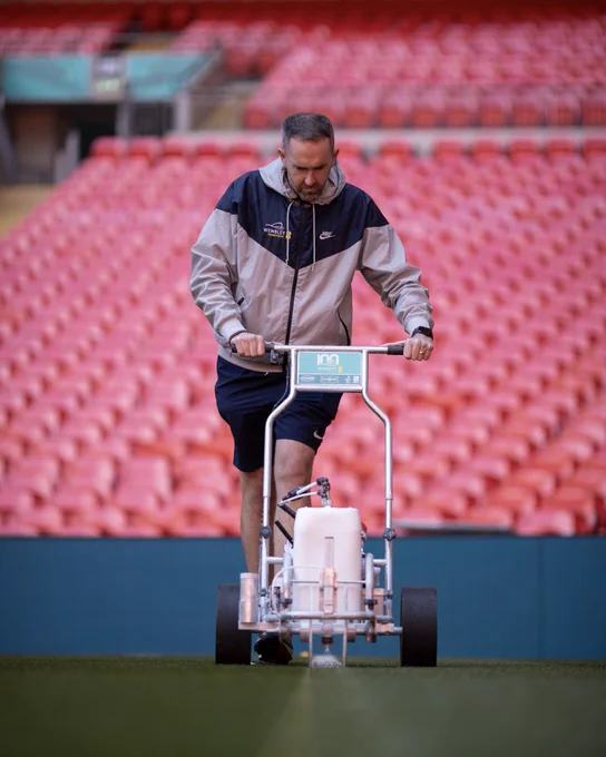 A picture of Karl Standley (Head Groundsman) at Wembley Stadium marking the pitch.
