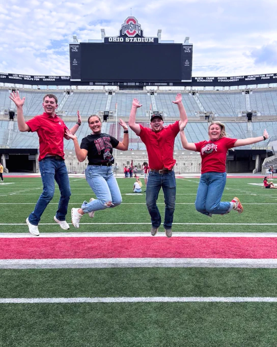 4 students jumping with excitement in the Ohio State Football Stadium. 