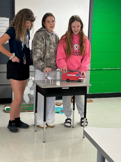 Students present their Hummingbird Robotics projects at the front of the classroom. 