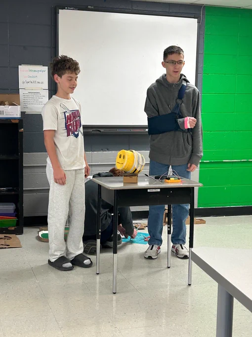 Students present their Hummingbird Robotics projects at the front of the classroom. 