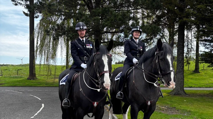 Two mounted police officers in uniform on black horses at Passing out Parade.