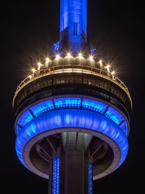 Closeup of the CN Tower at night lit blue/ Gros plan de la Tour CN illuminée en bleu la nuit 