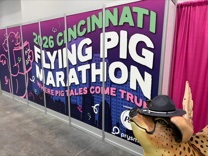 A picture of the 2026 Cincinnati Flying Pig Marathon banner and Flying Pig "statue" wearing an OSHP stetson.