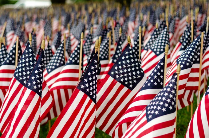 A field of small American flags closely arranged in rows, creating a sea of red, white, and blue.