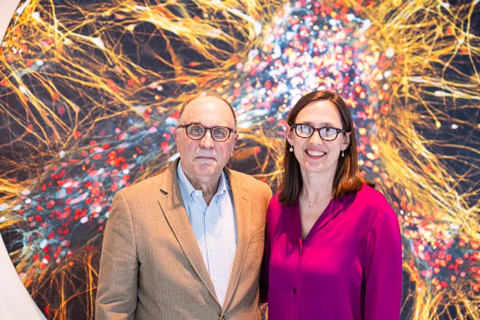 Photo of Michael Cima and Karen Daniel in front of a colorful scientific image in the Koch Institute Lobby. 