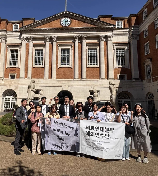 Delegates (doctors and nurses) from the KPTU union gathered in the courtyard of BMA House with a banner held up that says “Healthcare is not for sale” and “KPTU Healthcare Workers Solidarity division” and “Union exchange delegation to the U.K. and Australia” in English. I’m standing amidst the crowd.