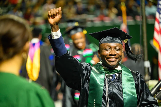 Ohio University grad raises a fist in celebration during commencement.