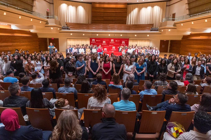 A photo of soon-to-be graduates standing up in the audience of Wentz Concert Hall to be recognized by their loved ones.