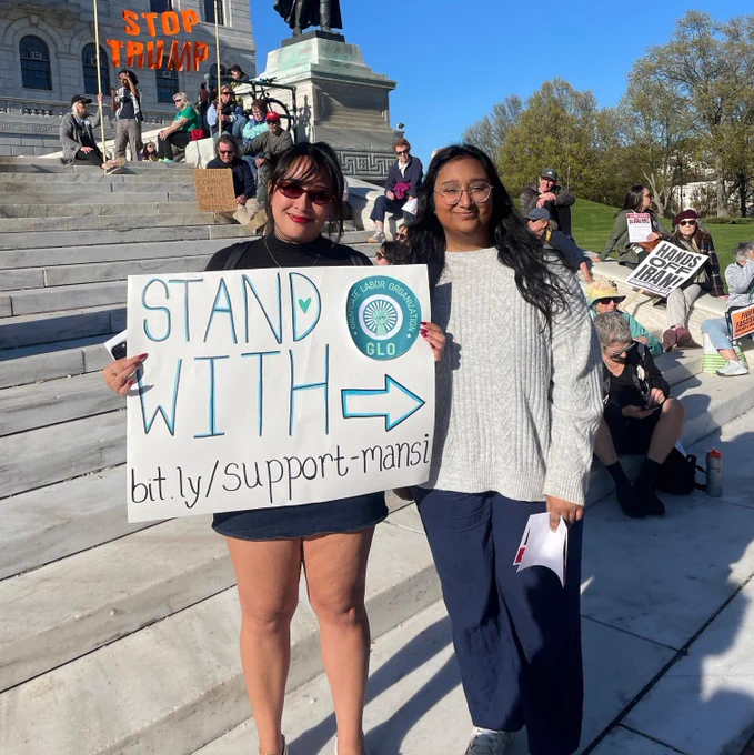 Two people stand with a poster that says "Stand with -> bit.ly/support-mansi"