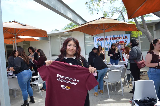 Liberal Studies senior holding up a t-shirt that says "Education is a Superpower."