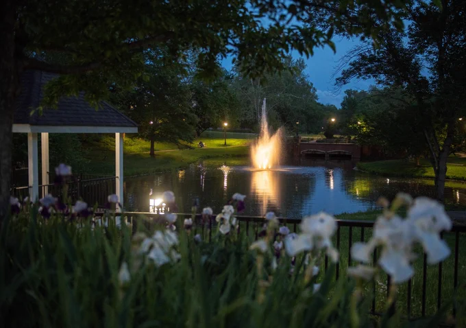 Emeriti Park at dusk with a water fountain lit up.