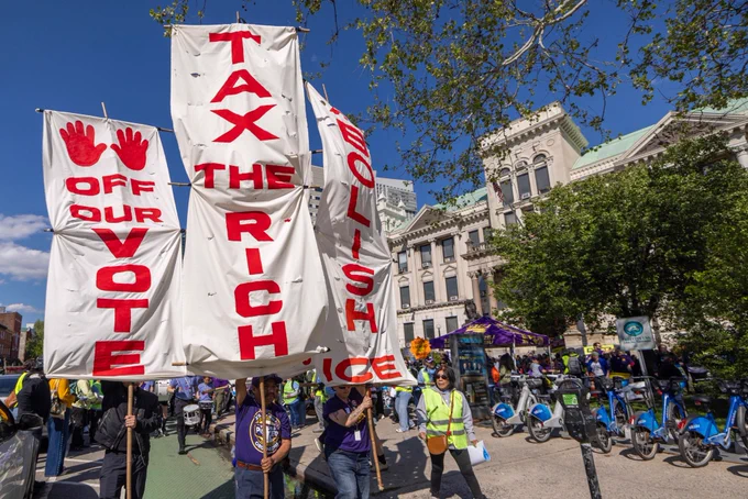 Signs saying “hands off our vote,” “tax the rich,” and “abolish ICE.”