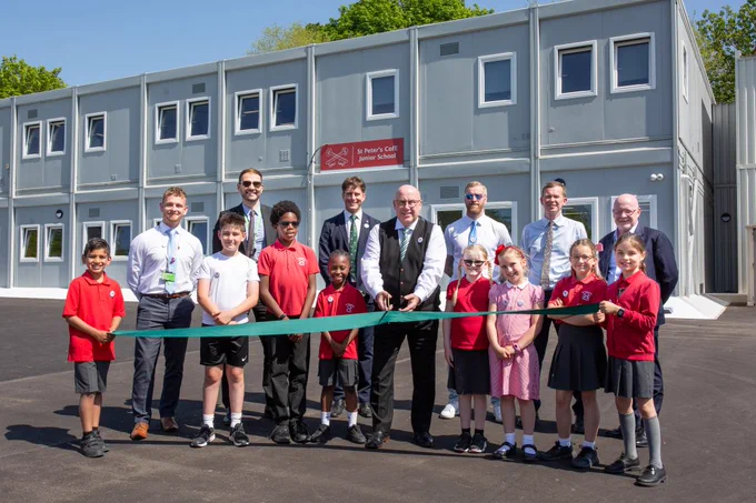 Pupils and councillors at St Peter's school, holding a dark green ribbon that is about to be cut.
