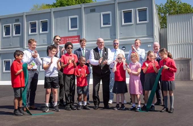 Pupils and councillors at St Peters school, holding a dark green ribbon that has been cut to celebrate the opening of the learning village.