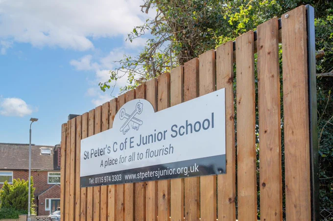 The entrance sign for St Peters Junior School on a wooden fence.
