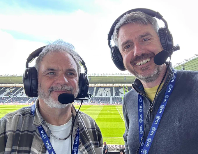 Landscape selfie of the DCFC AD commentators Robin and Stuart in front of the East stand in the background of the photo.