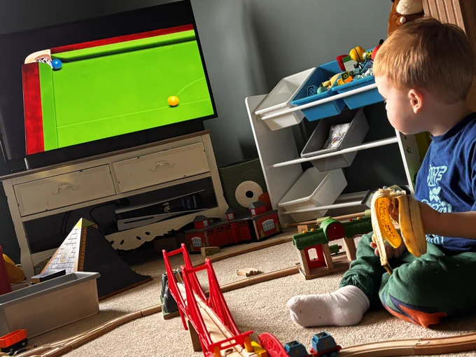 A photo of a toddler watching snooker on TV