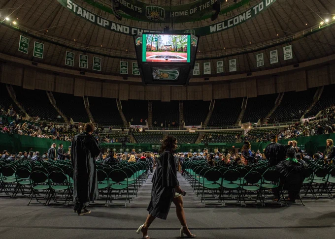 Ohio University graduate walks across floor in Convocation Center.