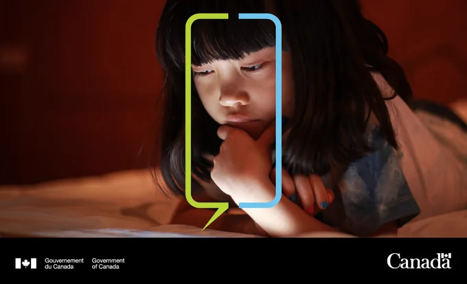 ALT : Image d’un jeune enfant au lit utilisant un téléphone cellulaire.

