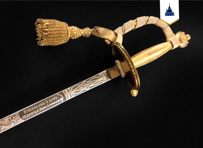 A sword made of silver with a gold handle and golden tassel.  