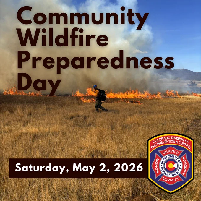 A wildland firefighter carrying a backpack and tools walks in front of a grass fire. The words Community Wildfire Preparedness Day, Saturday, May 2, 2026 are superimposed over the photo