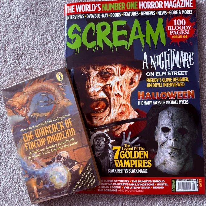 The cover of Scream horror magazine issue 96 with Freddy Kruger and Michael Myers on the cover. Also pictured is a first edition paperback copy of The Warlock of Firetop Mountain.