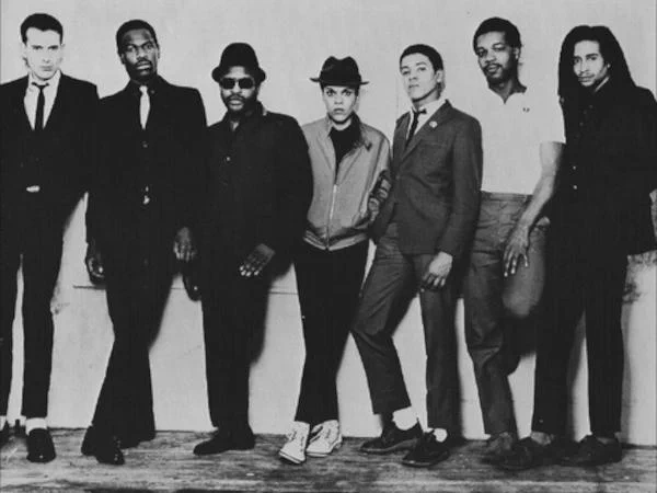 Black-and-white promotional photo of The Selecter circa early 1980s, featuring the full band lineup in classic 2 Tone styling with sharp suits and ska-influenced presentation.