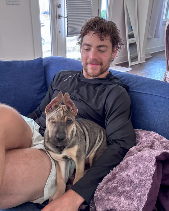 Image of Tyson Jost holding his new foster puppy Linguine on his lap